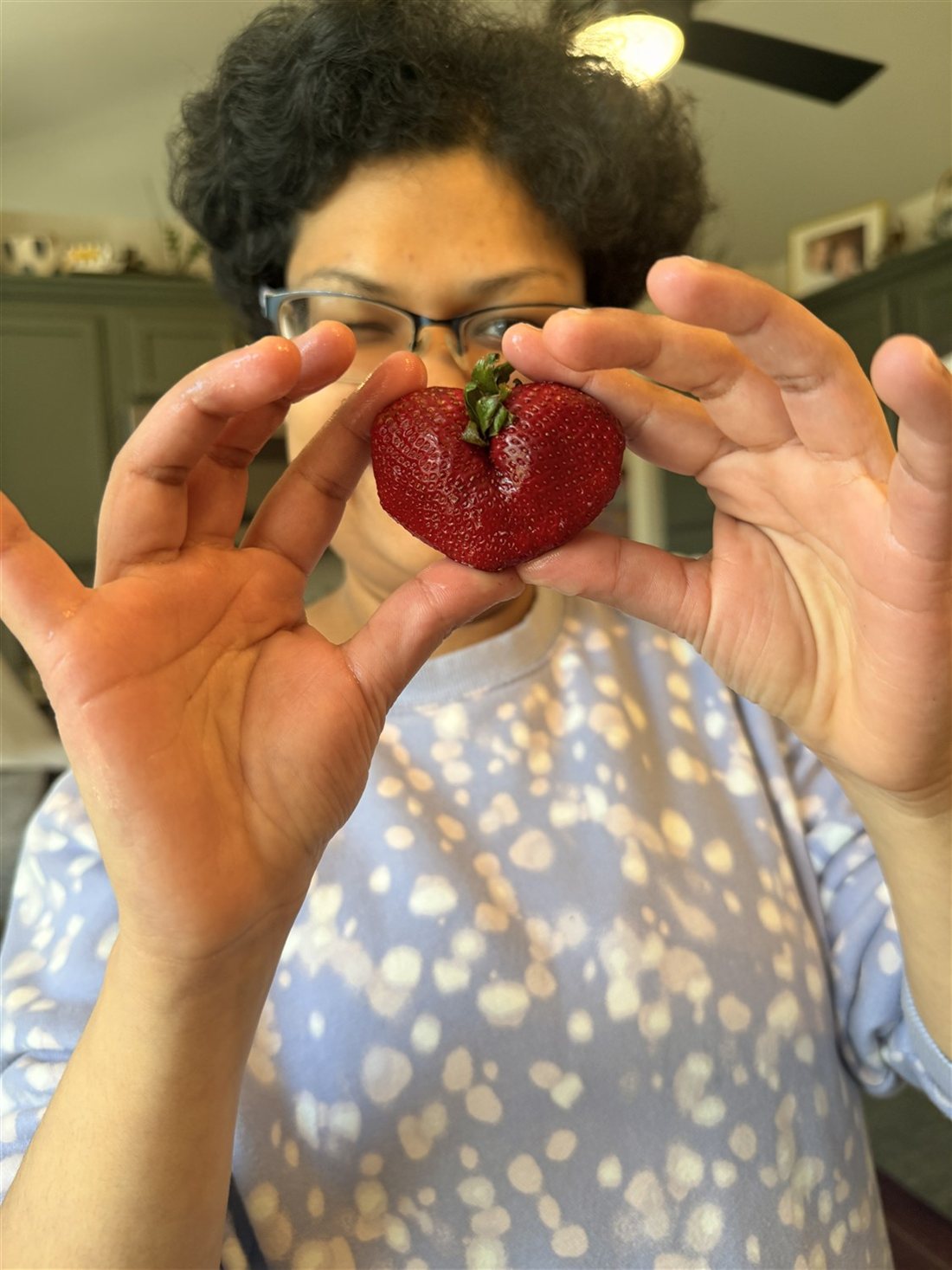 A Be Yourself Group member holding a heart-shaped strawberry in the kitchen