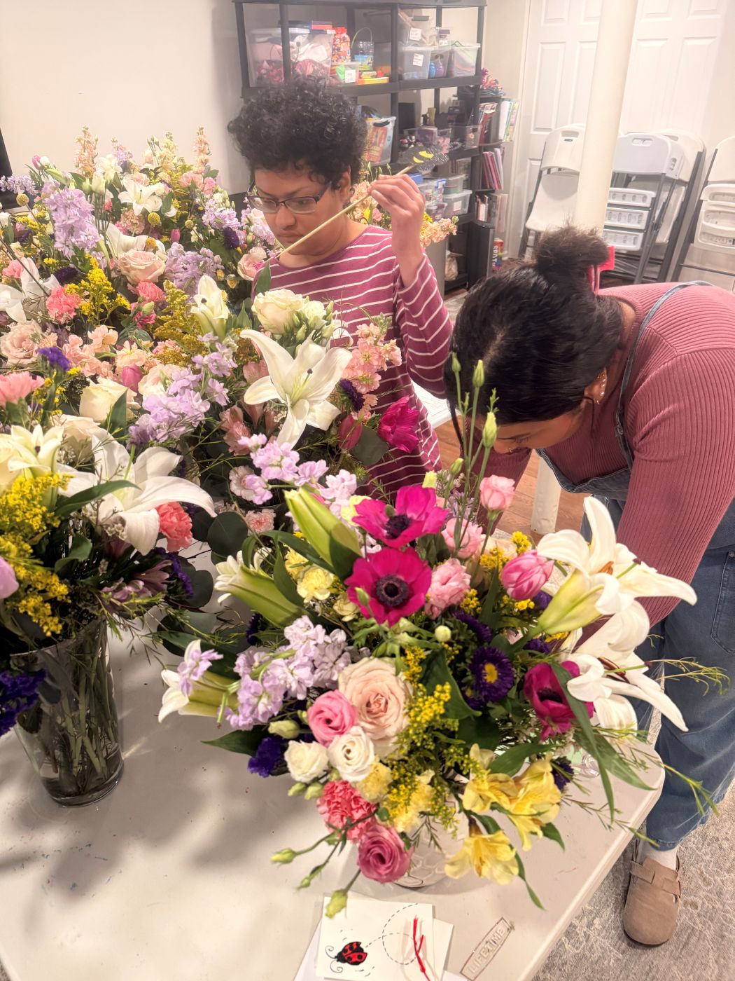 Two Be Yourself Flower Shoppe team members designing arrangements together, surrounded by fresh flowers