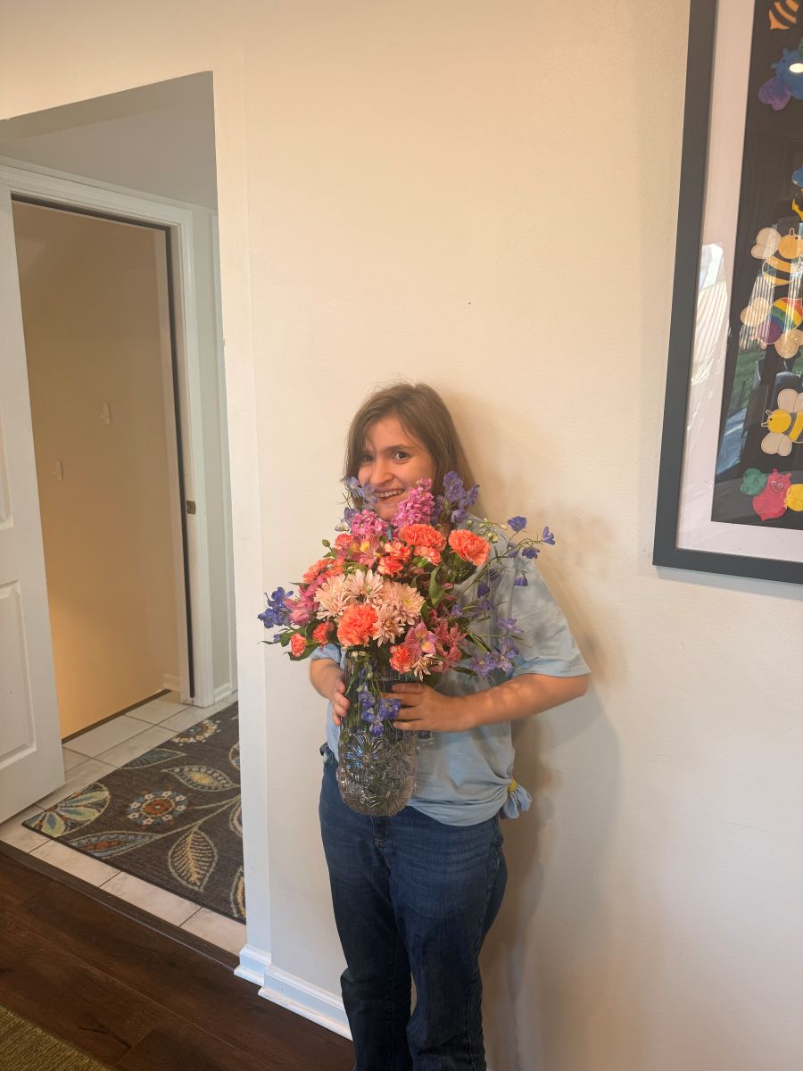 A team member smiling and holding the arrangement she made